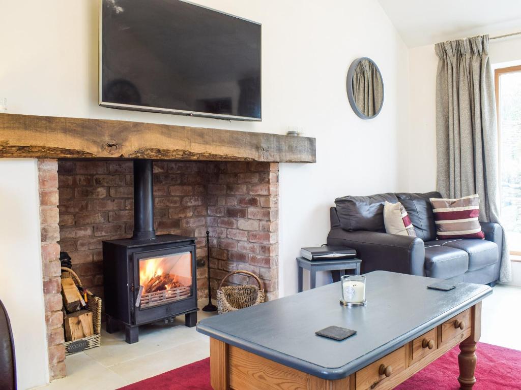 a living room with a couch and a fireplace at Holly Cottage Barn in Stoke Edith