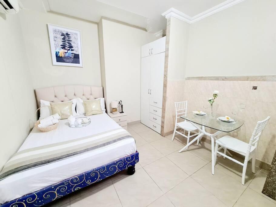 une chambre avec un lit, une table et des chaises dans l'établissement Estudio D2 Riocentro Norte-Mall Del Rio Samanes, à Guayaquil