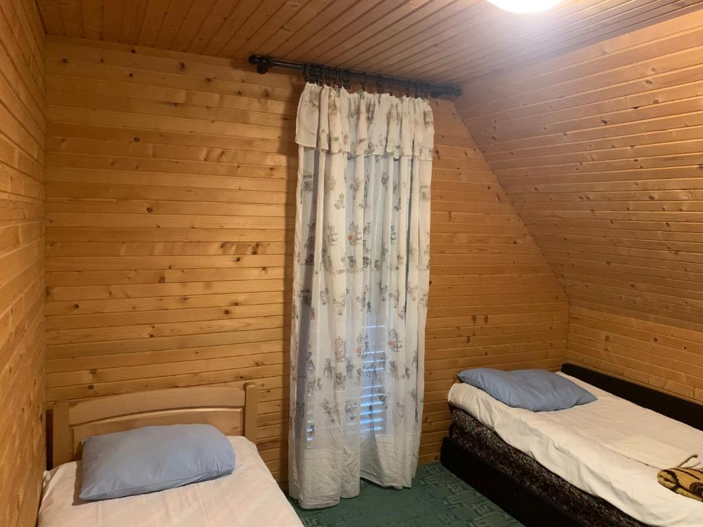 2 camas num quarto de madeira com uma janela em Guest House Đina em Žabljak
