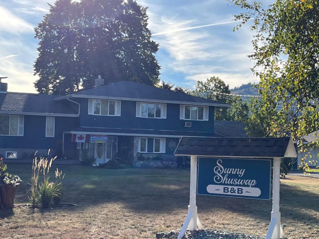 a blue house with a sign in front of it at Sunny Shuswap B&B in Chase