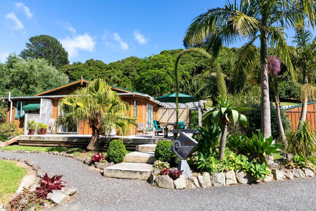 a house with a palm tree and a pathway at Aotea Lodge Great Barrier in Tryphena