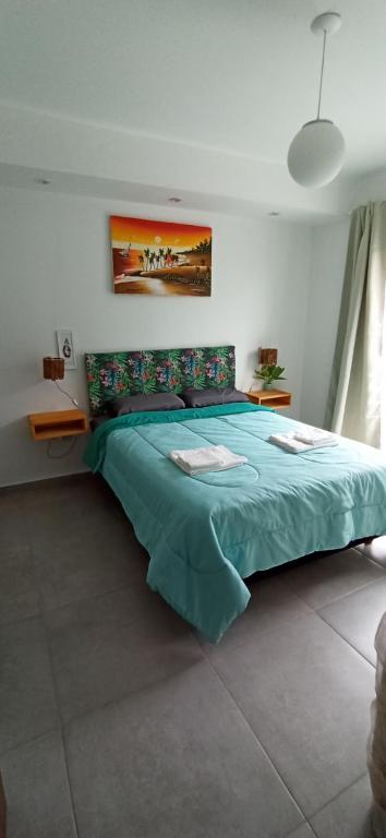 1 dormitorio con 1 cama grande con colcha verde en Plus Playa Unión en Playa Unión