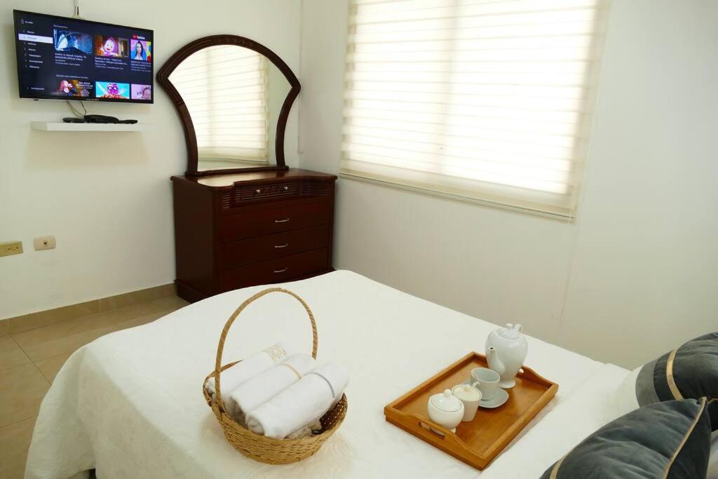 Una cama con una cesta de toallas y velas. en Condominio Charito Suite 2G a 12 Min Malecon 2000, en Guayaquil