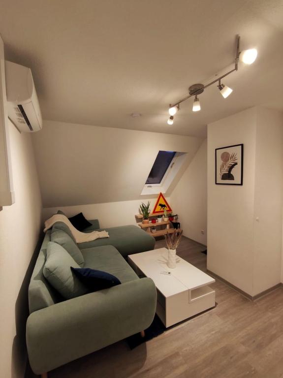 Dachgeschosswohnung mit Klimaanlage in bester Lage في مندن: غرفة معيشة مع أريكة خضراء وطاولة
