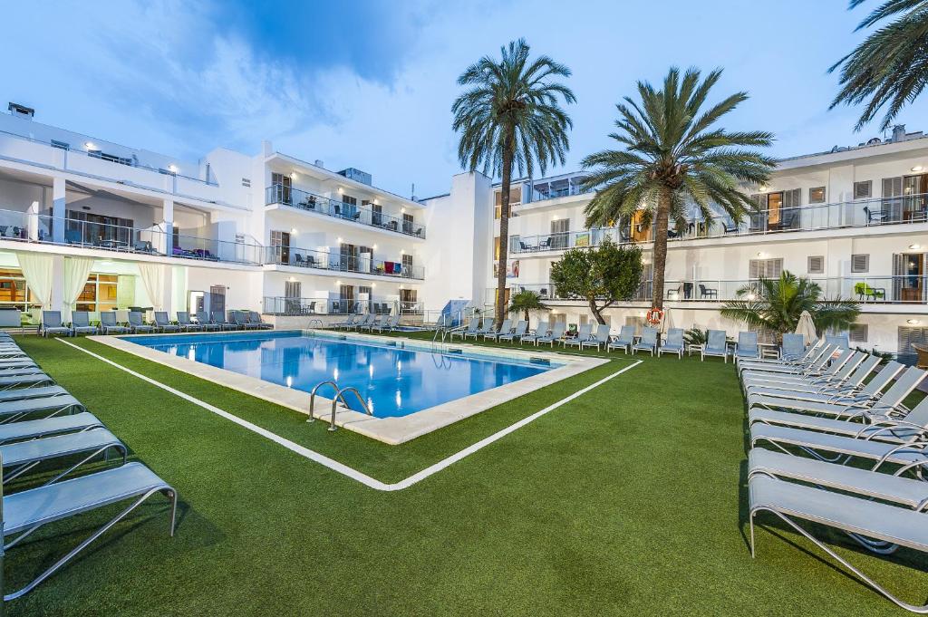 a hotel with a pool and chairs and palm trees at Eix Alcudia Hotel Adults Only in Port d'Alcudia