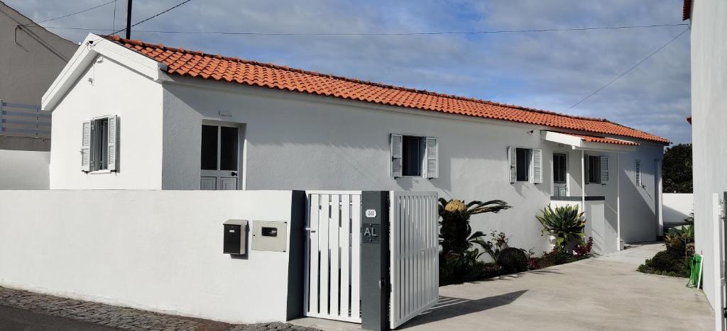 ein weißes Haus mit einem Tor davor in der Unterkunft Casa da Avó Biza in São Roque do Pico