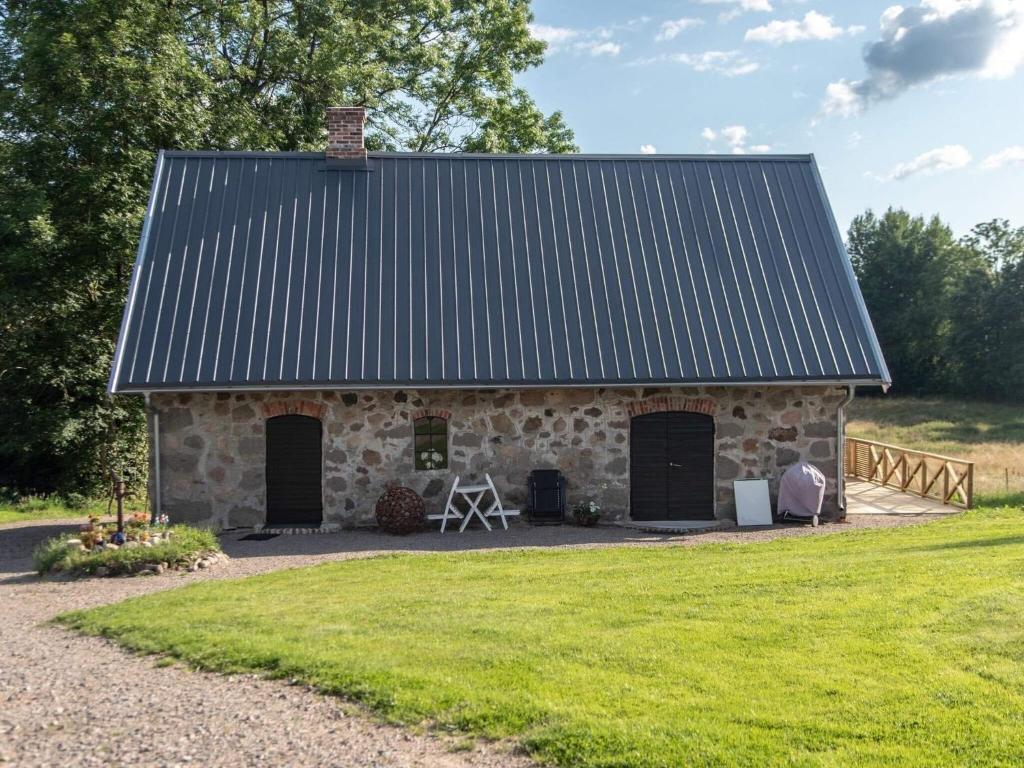 a stone barn with a metal roof and grass at Holiday home SIMLÅNGSDALEN IV in Simlångsdalen