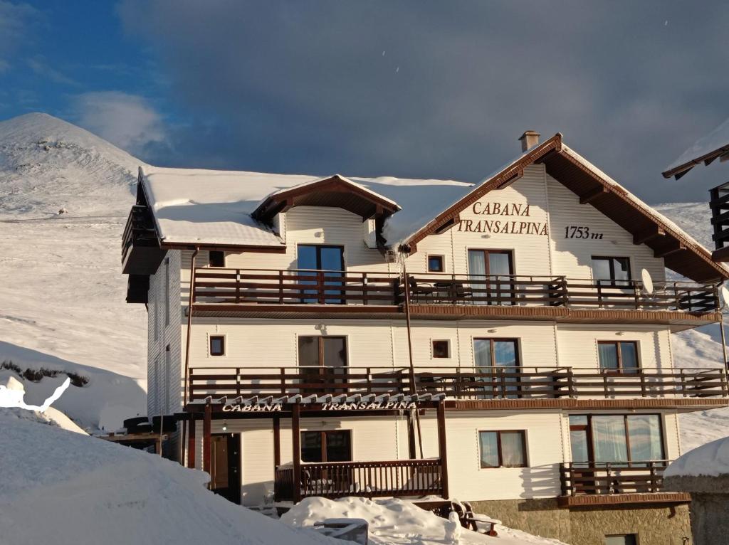 un edificio en la cima de una montaña cubierta de nieve en Cabana Transalpina, en Ranca