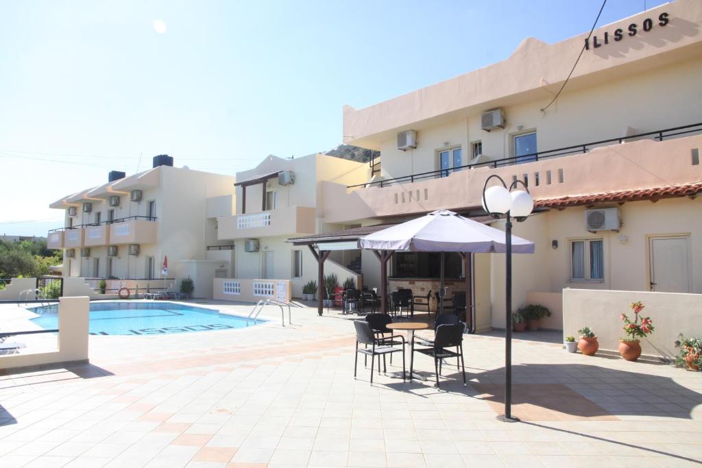 hotel z basenem i stołem z krzesłami i parasolem w obiekcie ilissos Apartments w mieście Stalida