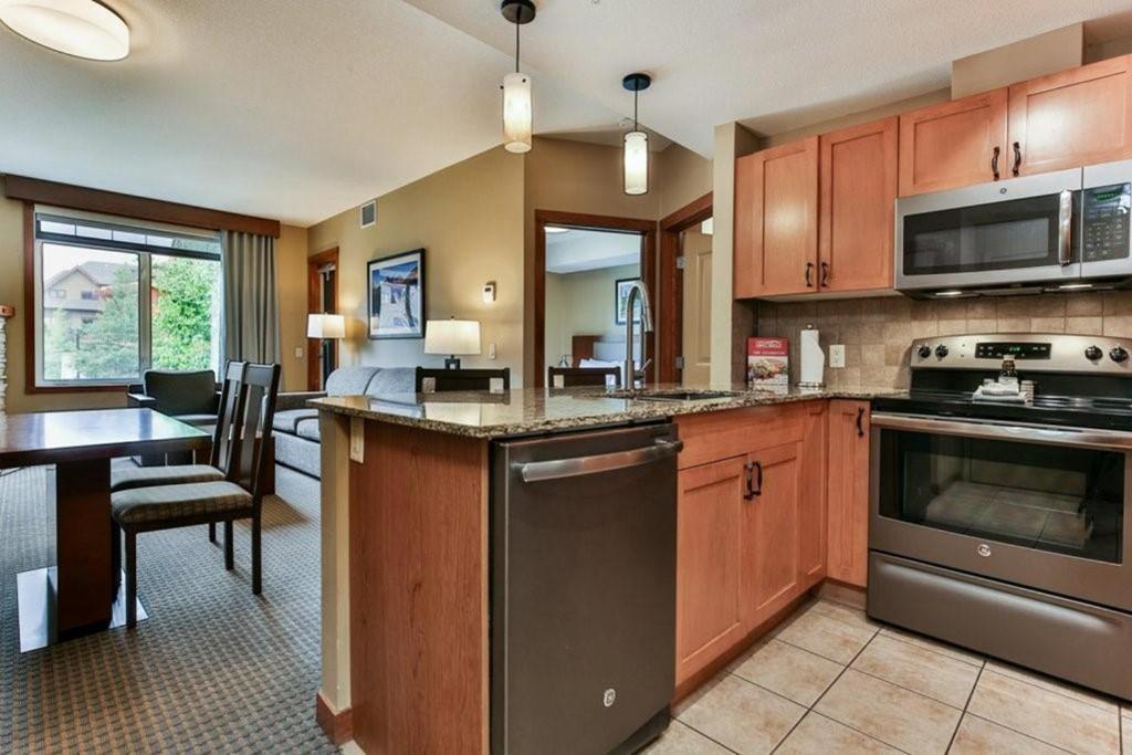 eine Küche mit Holzschränken, einem Tisch und einem Esszimmer in der Unterkunft B&B Falcon Crest Lodge 1BR 1Pullout in Canmore