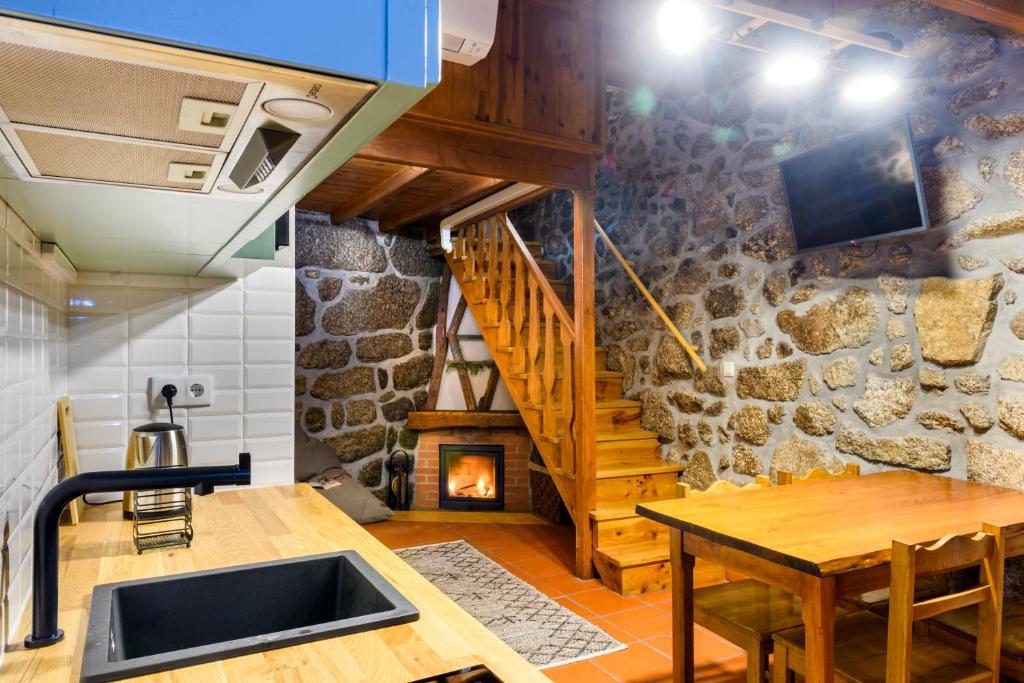 a kitchen with a table and a stone wall at Casa do Tio Ferreiro in Sabugueiro
