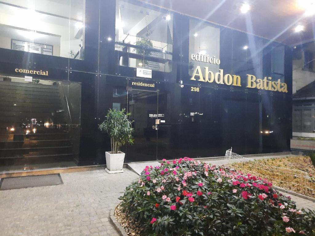 a store front of a building with flowers in front at AP Abdon Central Temporada in Joinville