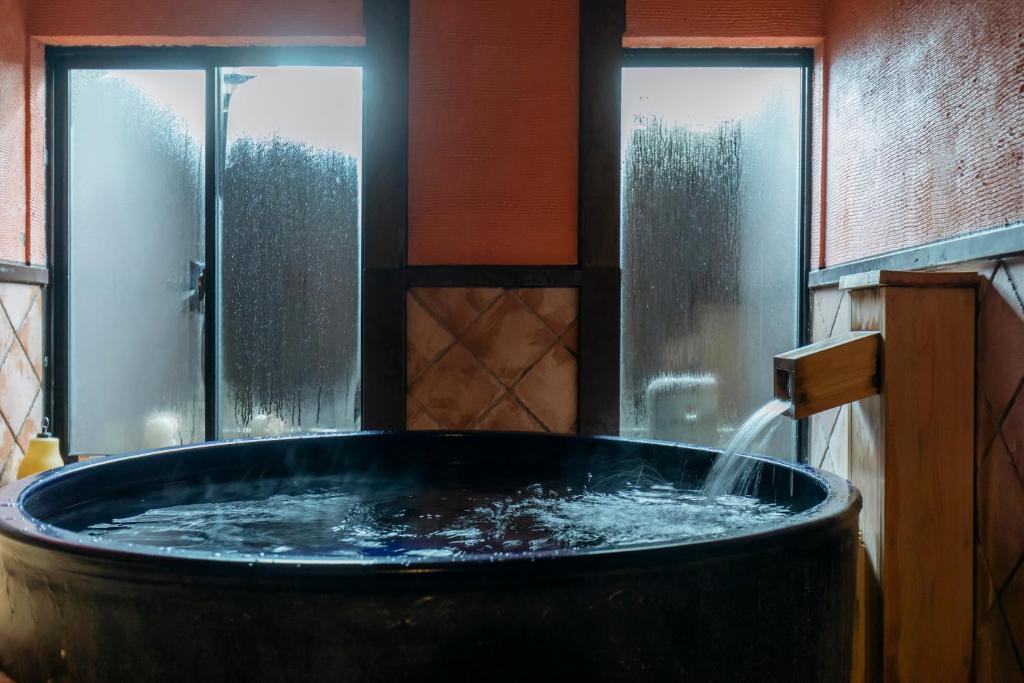 a large tub with water in a room with windows at Sensui in Toyooka