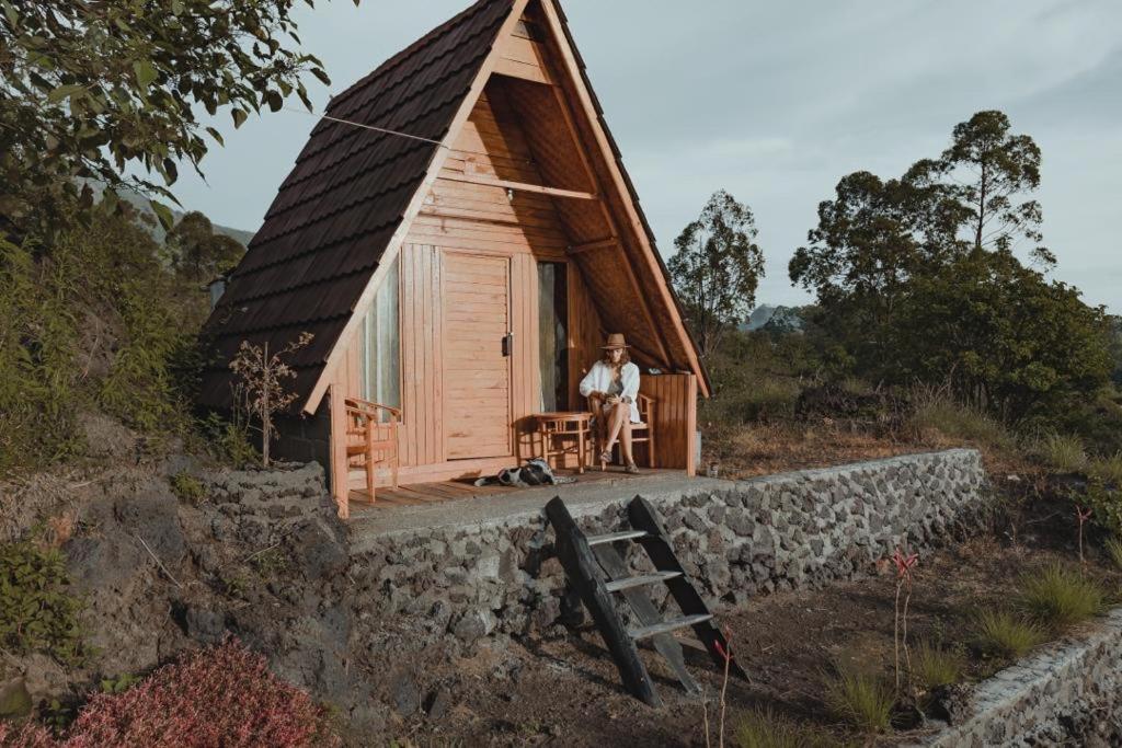 Un uomo seduto di fronte a una piccola casa di D' Tepi Danau Glamping a Kintamani