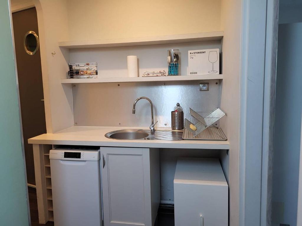 a small kitchen with a sink and shelves at Appartement Merville-Franceville-Plage, 3 pièces, 6 personnes - FR-1-465-87 in Merville-Franceville-Plage