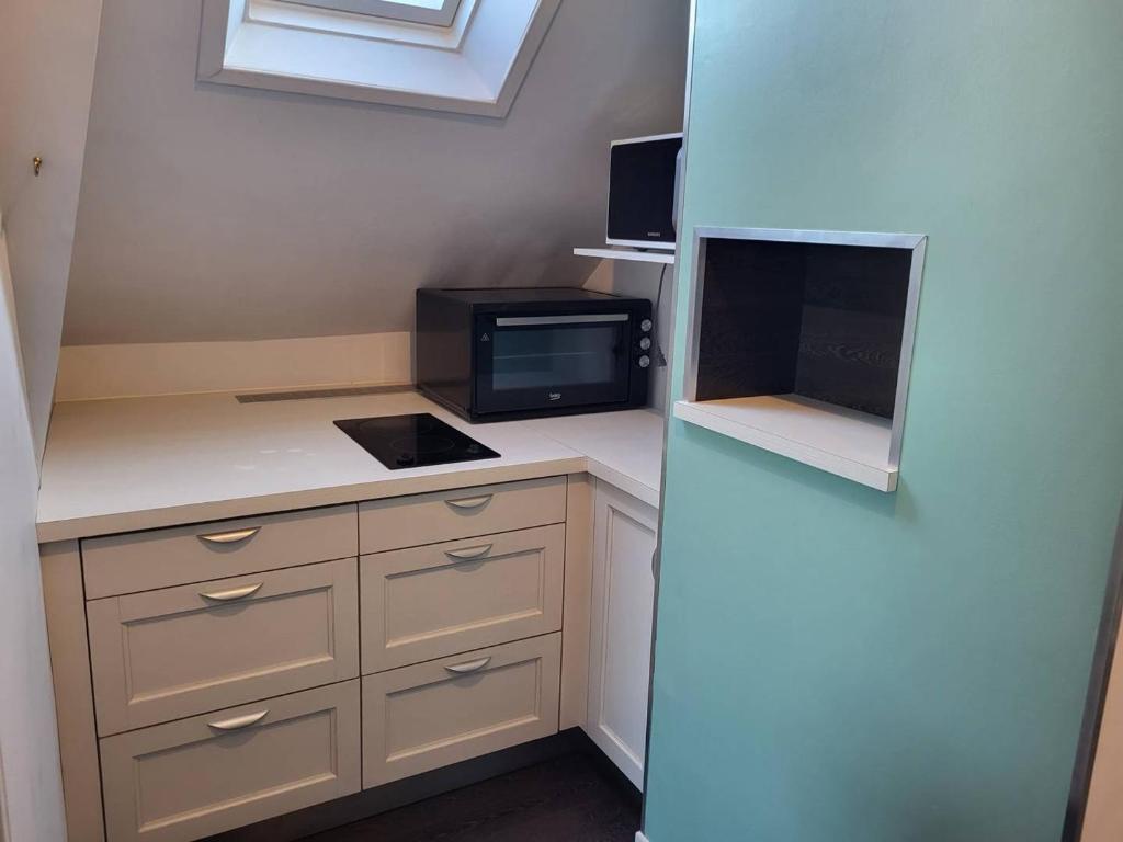 a small kitchen with a refrigerator and a microwave at Appartement Merville-Franceville-Plage, 3 pièces, 6 personnes - FR-1-465-87 in Merville-Franceville-Plage