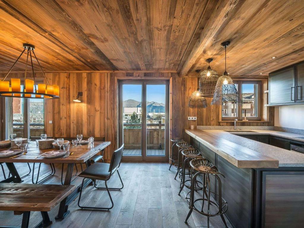 une cuisine avec des murs en bois et un long comptoir avec des chaises dans l'établissement Appartement spacieux de 4 chambres à Courchevel 1850, à 250m des remontées mécaniques et des commerces - FR-1-564-93, à Courchevel
