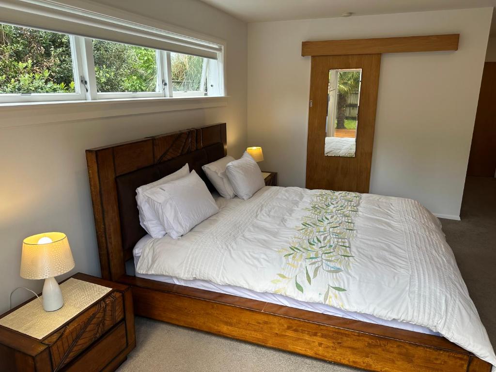 a bedroom with a large wooden bed and a window at The perfect getaway for two in a large suite in Whanganui