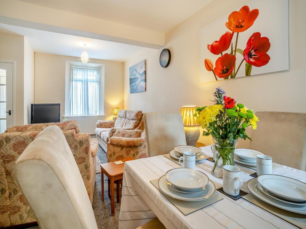 a living room with a table with red flowers on it at Lime House in Gorseinon