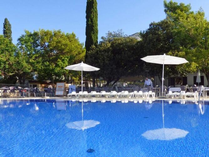 a swimming pool with umbrellas and tables and chairs at Caravan park Paklenica Starigrad Paklenica - CDN05014-MYA in Starigrad-Paklenica