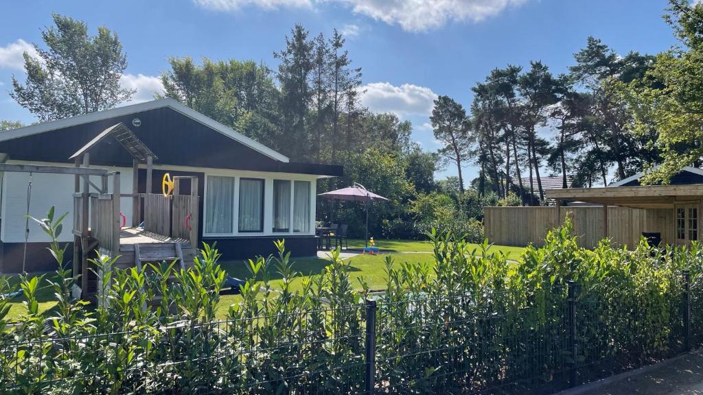 a small house in a yard with a fence at Bungalow Bavelds Home - Denekamp in Denekamp