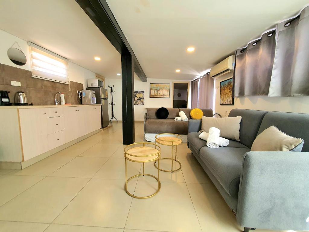 ein Wohnzimmer mit einem Sofa und Tischen sowie eine Küche in der Unterkunft Barak Royal Suites 20 sea view - ג'קוזי בחצר ומרפסות עם נוף לים in Eilat