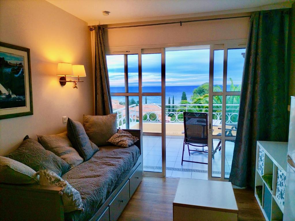 a living room with a couch and a balcony at Superbe Appartement avec vue Mer et Piscine in Saint-Raphaël