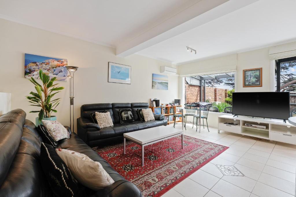 a living room with a leather couch and a tv at Black Dolphin Waterfront Apartment in San Remo