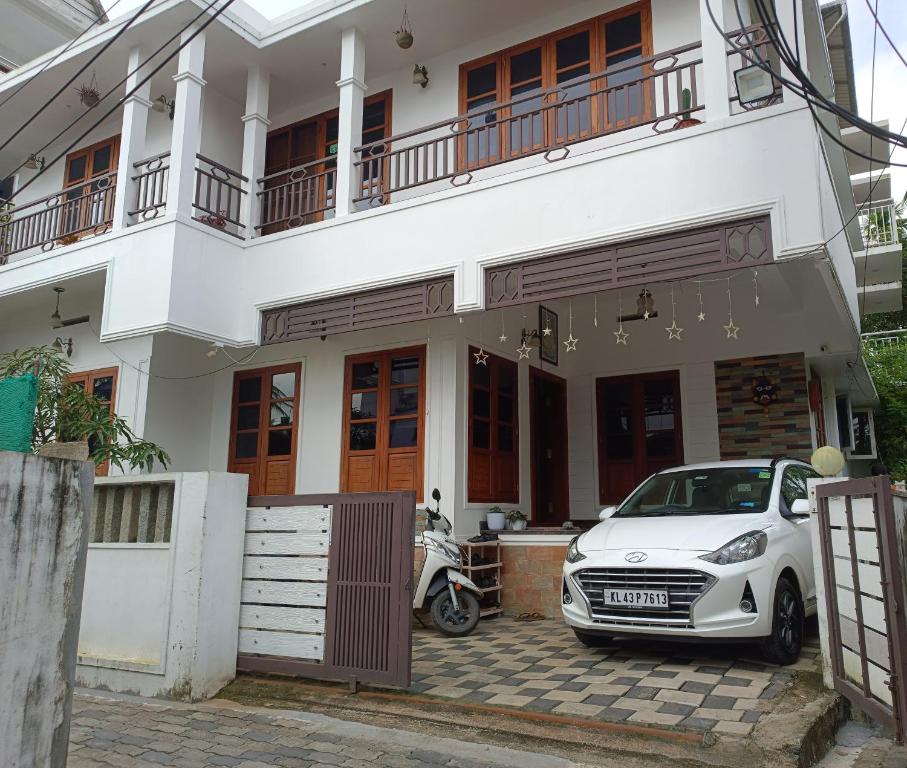 a white car parked in front of a house at PRAKRITI HOMESTAY Fortkochi Air Conditioned Rooms in Cochin