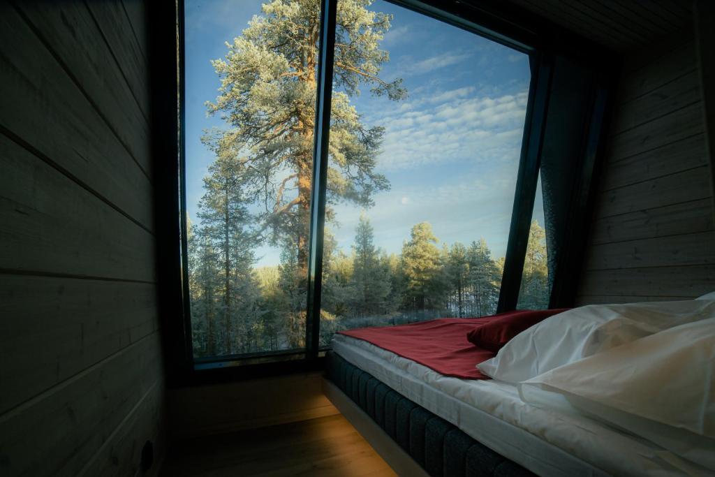 Cama en habitación con ventana grande en Salla Wilderness Lodges, en Salla