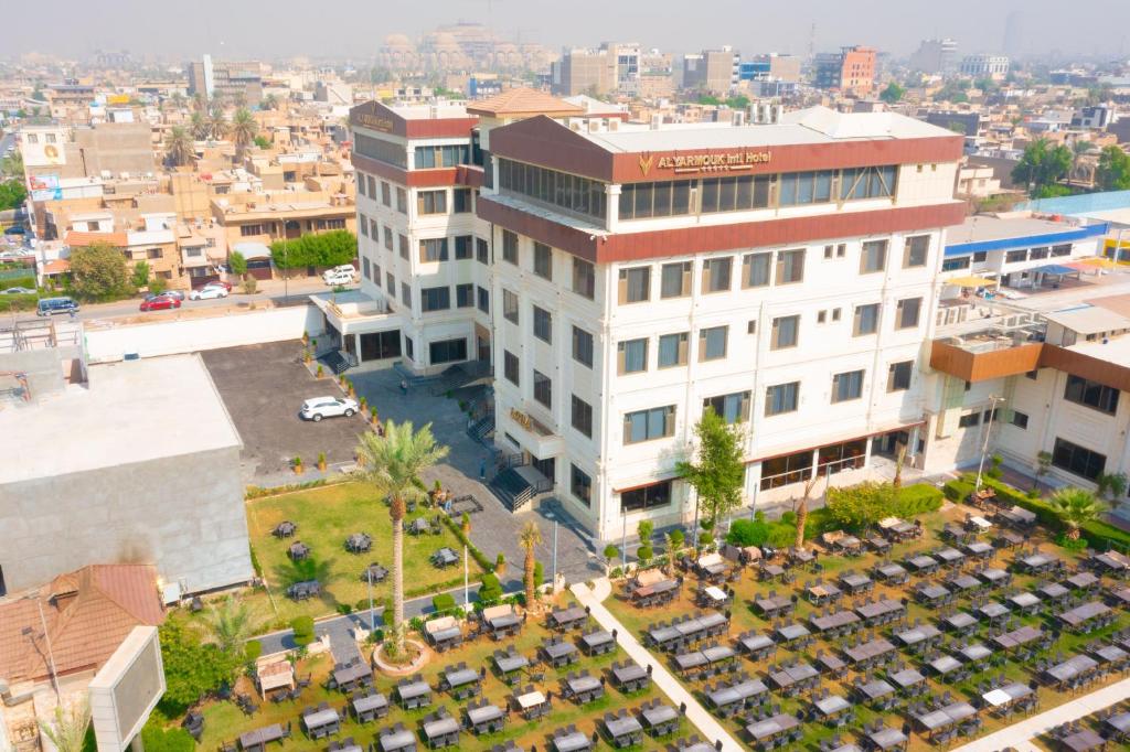 una vista in alto di un edificio con auto parcheggiate in un parcheggio di Al Yarmouk International Hotel a Baghdād