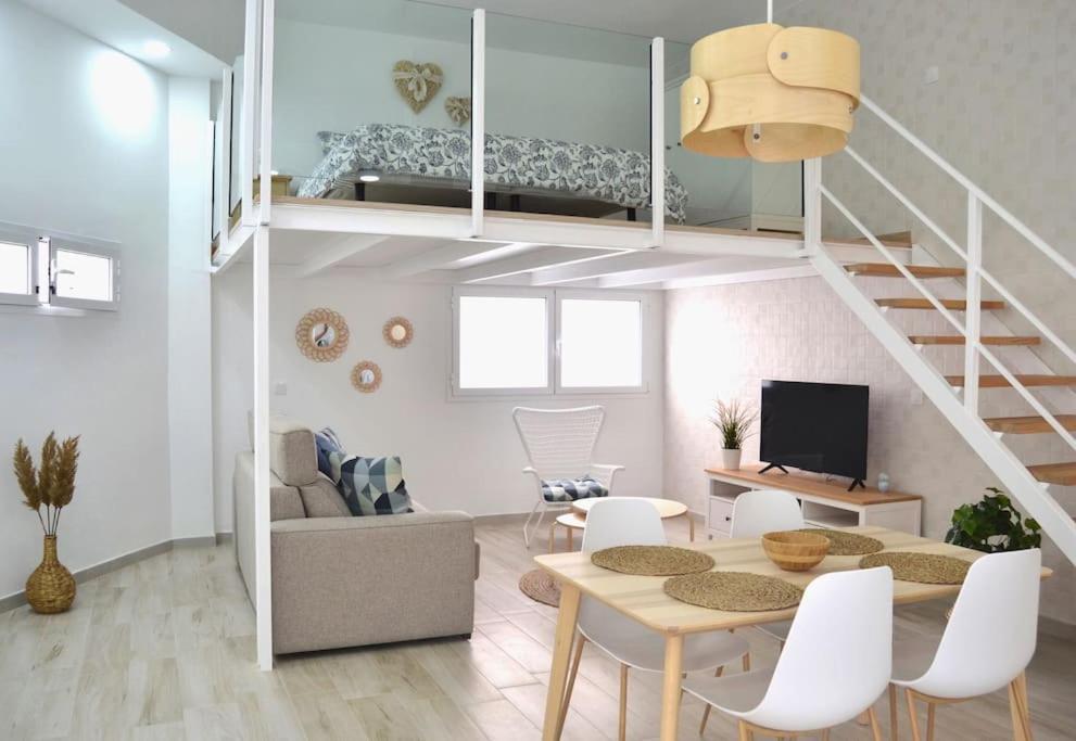 sala de estar con escalera, mesa y sillas en Loft Sol y Luna en Las Palmas de Gran Canaria, en Las Palmas de Gran Canaria