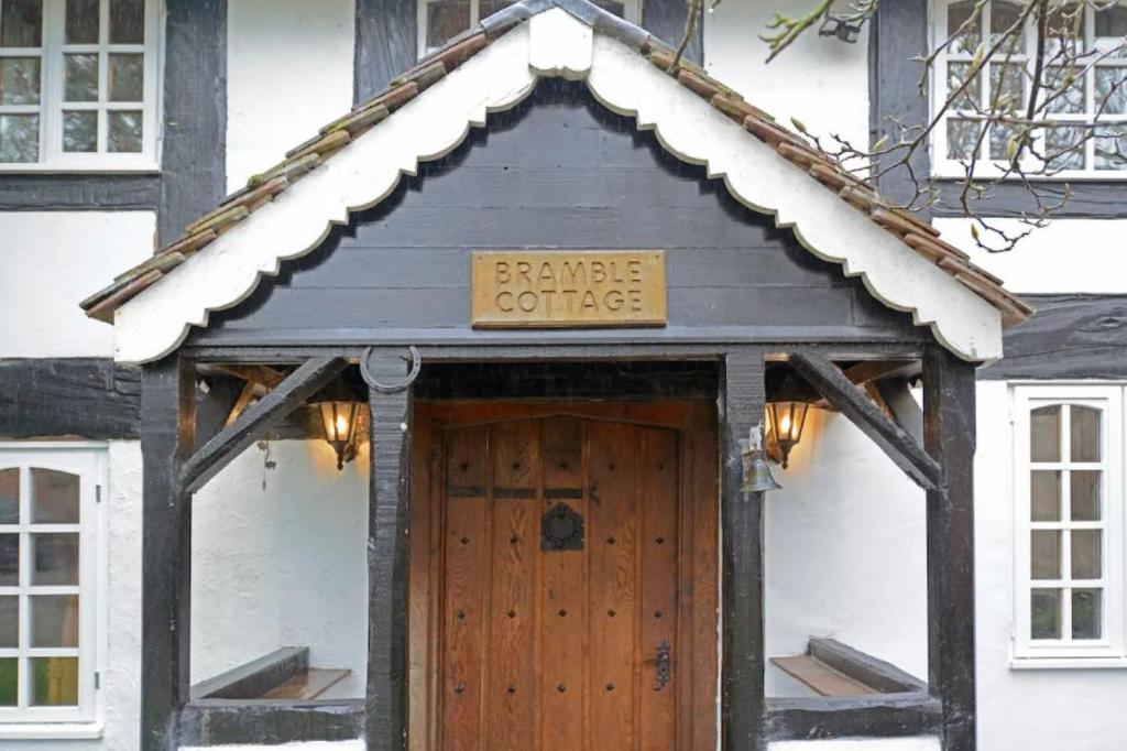 una casa con una puerta de madera con un cartel encima en Pass the Keys Shrewsbury Grade 2 Listed Black White Cottage en Shrewsbury