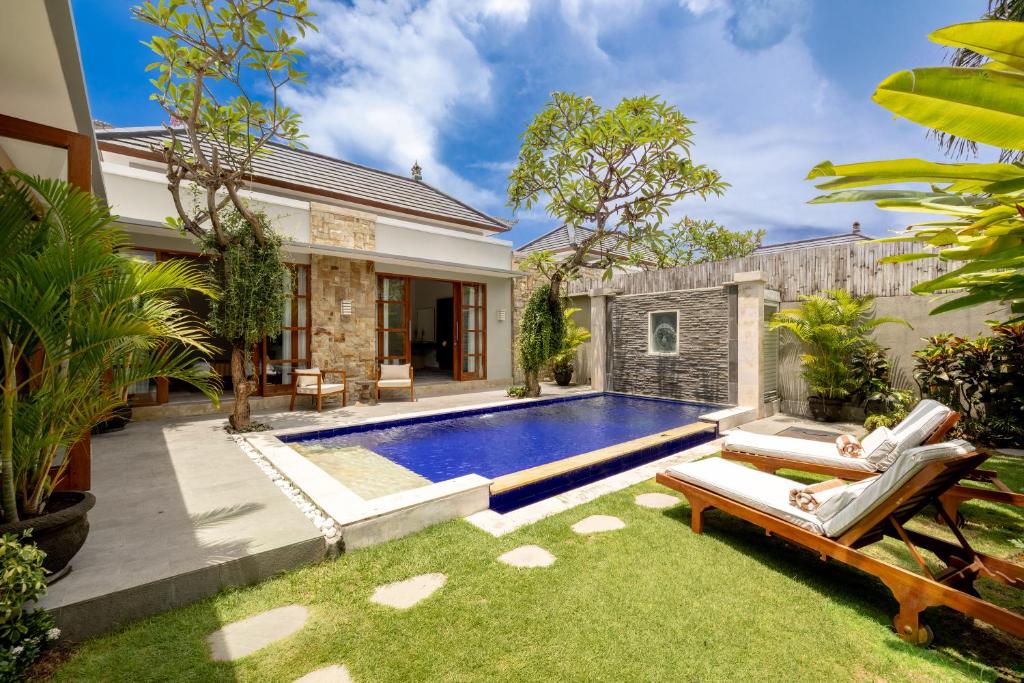 a backyard with a swimming pool and a house at Bali Voyage in Seminyak