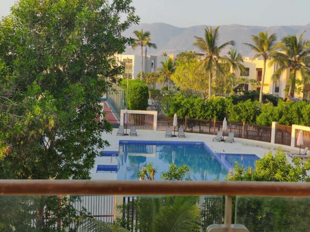 a view of a swimming pool with palm trees and buildings at Hawana Salalah Laguna Studio in Salalah
