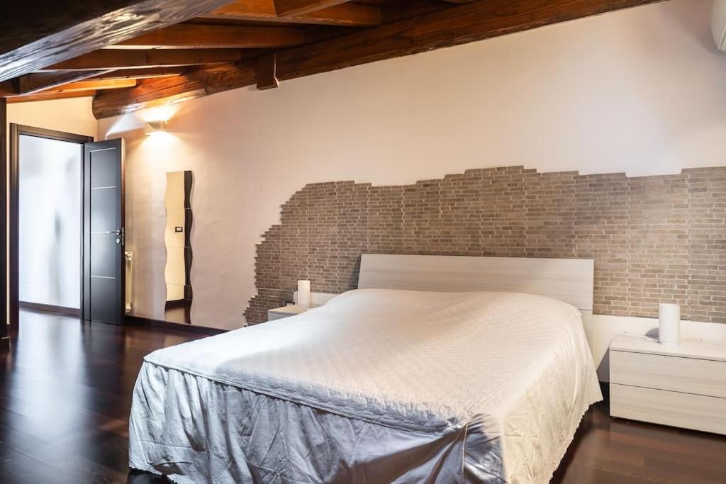 1 dormitorio con cama blanca y pared de ladrillo en Caronni 52 Villa Country & Business Ostia Antica, en Ostia Antica