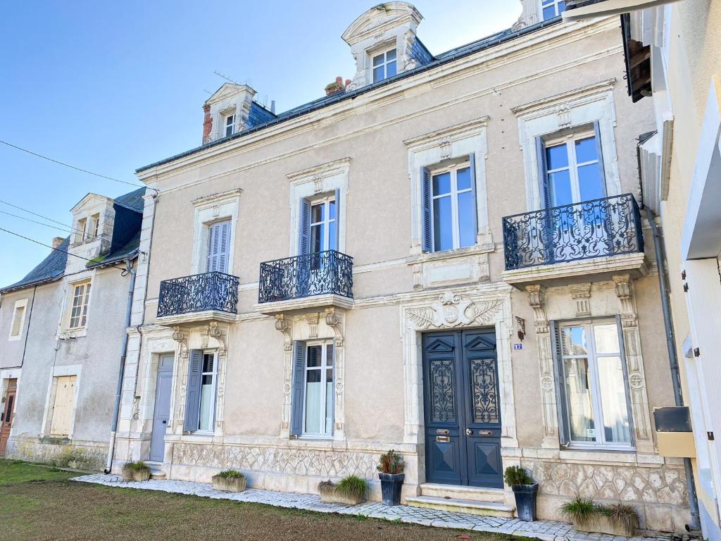 Una gran casa blanca con una puerta azul en Closerie la Fontaine, en Savigné-sur-Lathan
