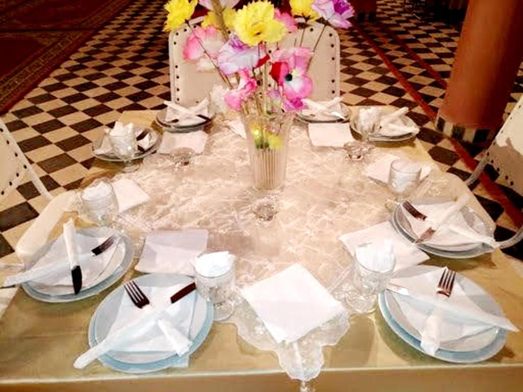 une table avec des assiettes et un vase de fleurs dans l'établissement kasbah Dar Bahnini, à Skoura