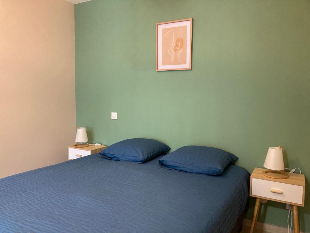 1 dormitorio con 1 cama azul y 2 mesitas de noche en Clos du Béron- Appartement meublé de tourisme, en Cappelle-en-Pévèle