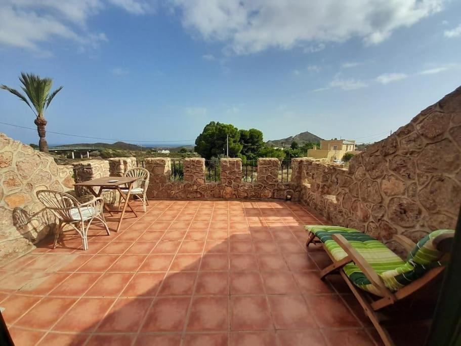 a patio with chairs and a table and a stone wall at El Retiro - Casa Vibrante in Pilar de Jaravía