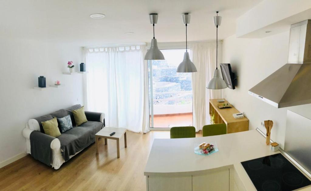 eine Küche und ein Wohnzimmer mit einem Sofa und einem Tisch in der Unterkunft Apartamento a pie de playa Tabaiba, Santa Cruz de Tenerife in Tabaiba