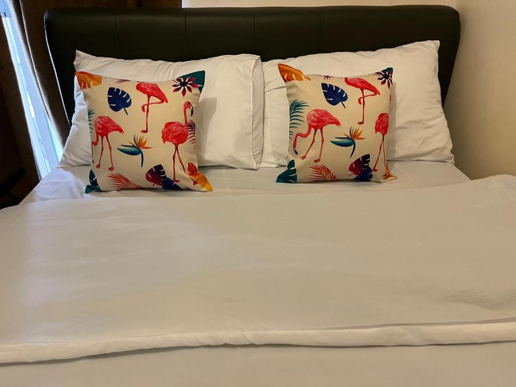 een bed met witte lakens en kussens met rode bloemen bij Fairway Terraces Resort Staycation in Manilla