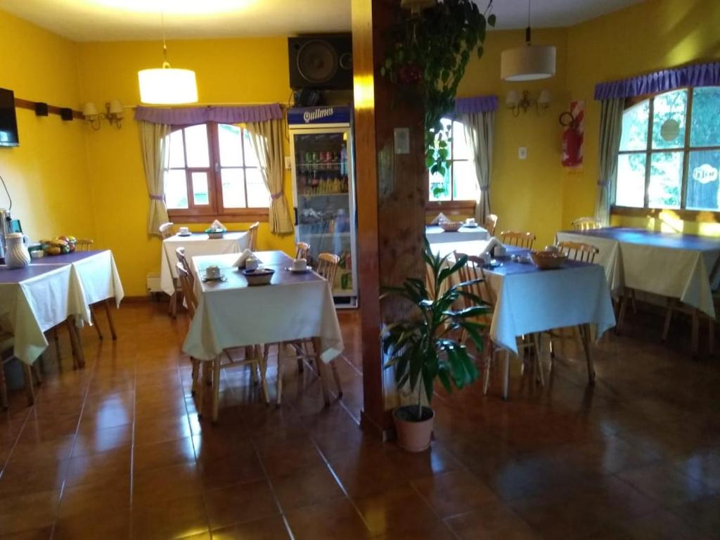 un restaurante con mesas y sillas blancas y ventanas en Posada de la Flor en San Carlos de Bariloche