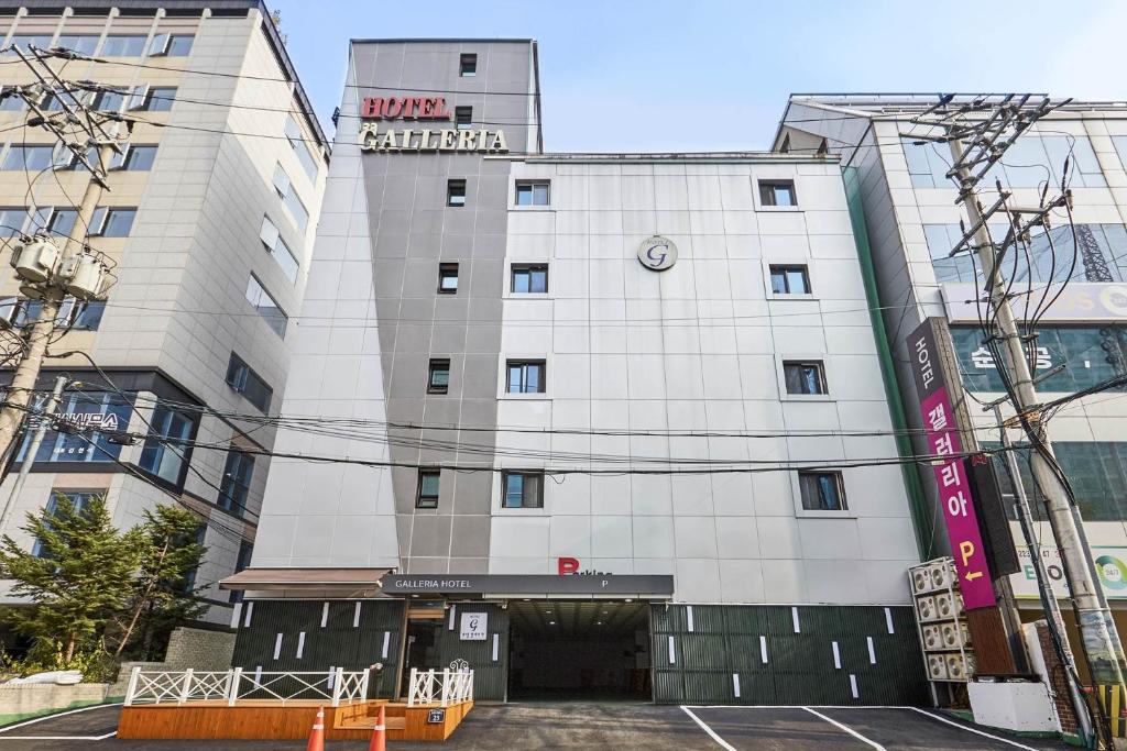 un edificio blanco con un reloj en él en Galleria Hotel, en Suwon