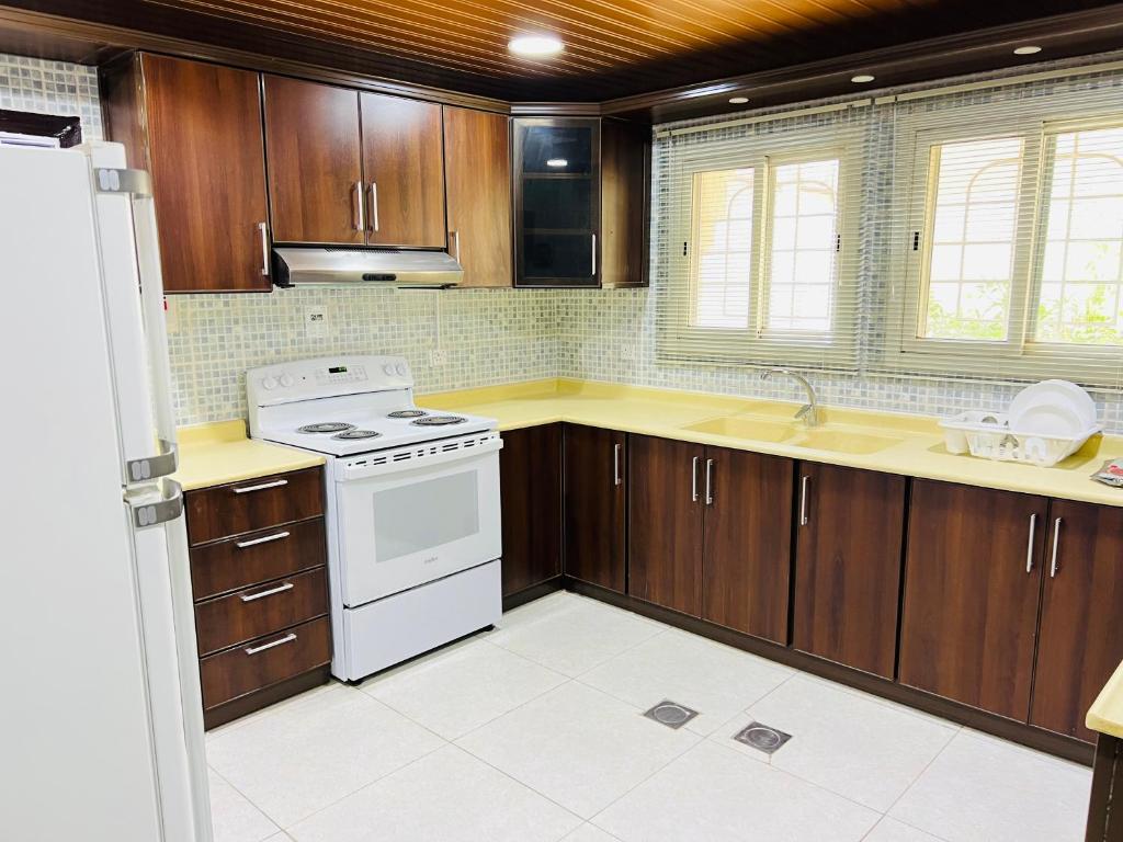 una cucina con armadi in legno e un piano cottura bianco con forno di FANATEER SUDAYER VILLA a Al Fanātīr