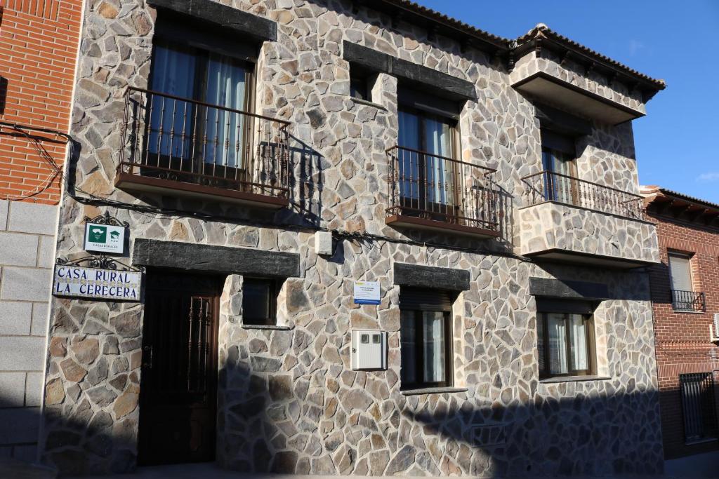 Los NavalucillosにあるCasa Rural "La Cerecera"の窓とバルコニーが備わる石造りの建物