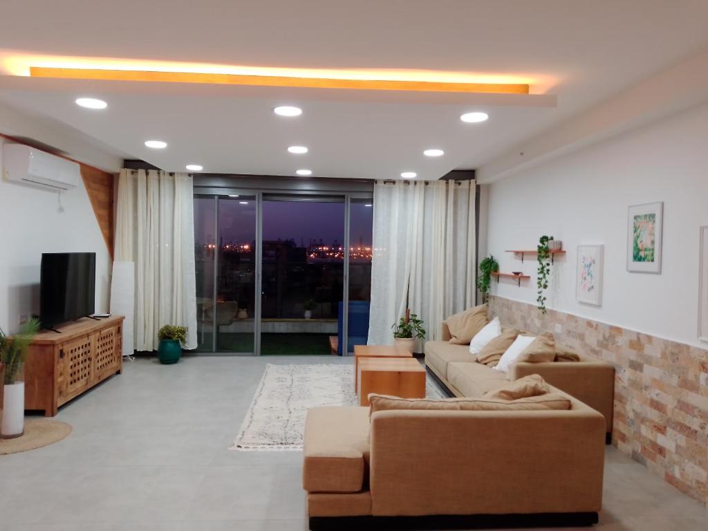 a living room with a couch and a tv at Beautiful beach apartment in Ashdod