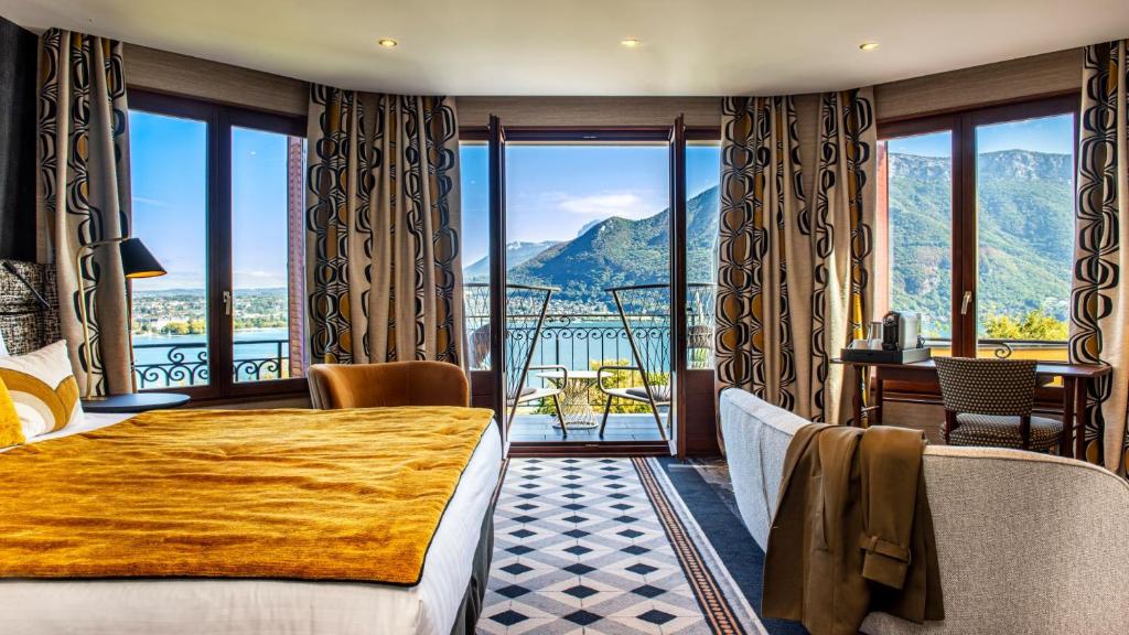 a hotel room with a bed and a balcony with mountains at Les Trésoms Lake and Spa Resort in Annecy
