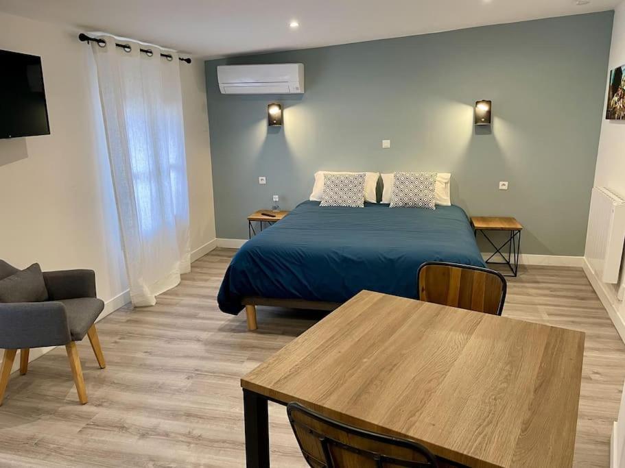 ein Schlafzimmer mit einem Bett und einem Tisch in einem Zimmer in der Unterkunft Le Moulin 3 - Appartement Tout Confort Centre Ville - Beziers - Wifi - Tv connecté in Béziers