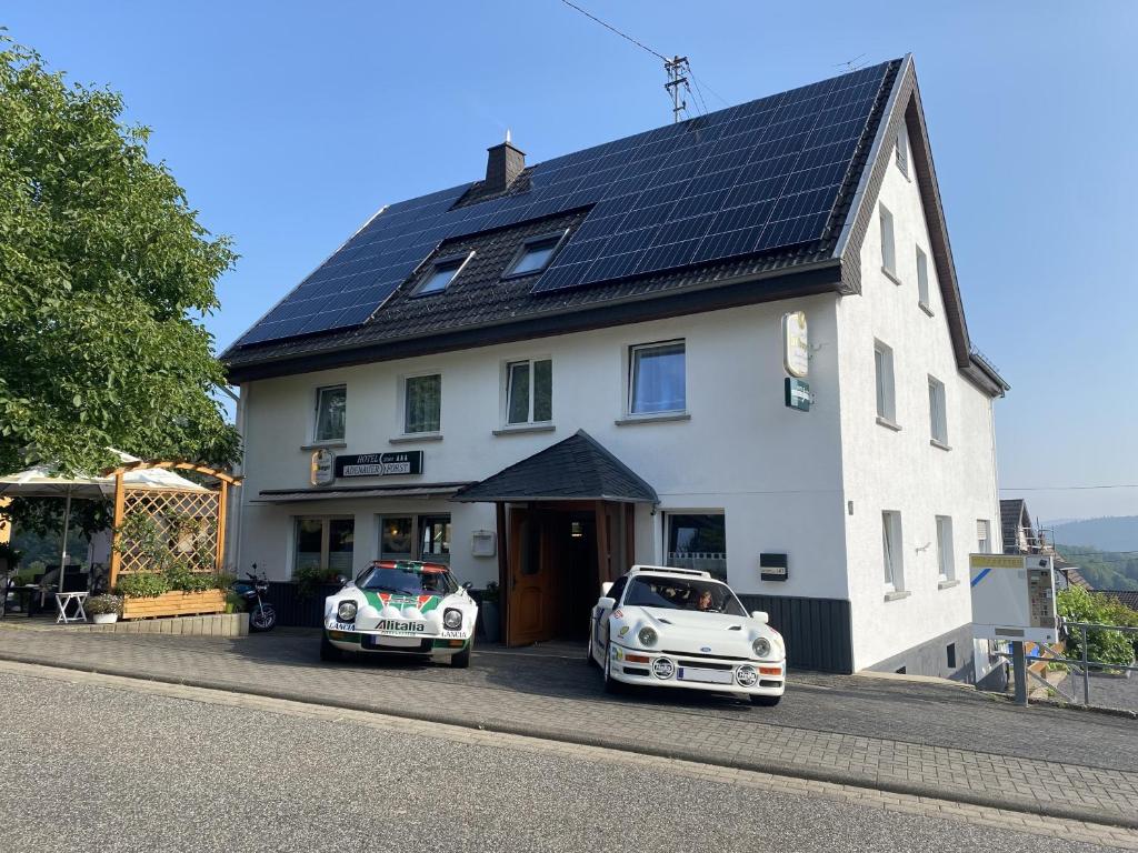 deux voitures garées devant une maison équipée de panneaux solaires dans l'établissement Hotel garni Zum Adenauer Forst, à Wimbach